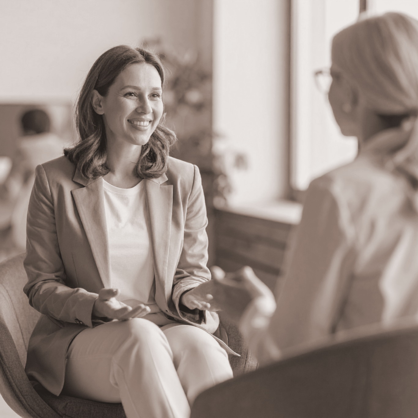 Zwei Frauen im Gespräch in einem modernen Büroumfeld, freundlich und interessiert.